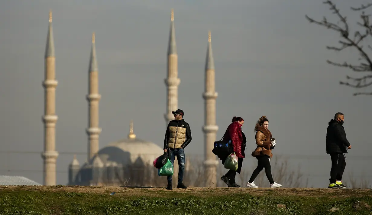 Turis Bulgaria berjalan menuju mobil dengan tas belanja di Edirne, dekat perbatasan Bulgaria, di Turki, pada 24 Desember 2021. Warga Bulgaria melintasi perbatasan barat Turki dengan mobil dan bus yang penuh sesak, memanfaatkan penurunan lira Turki untuk membeli barang-barang. (AP Photo/Emrah Gurel)