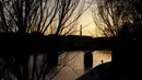 Seorang pria berjalan di tepi sungai Seine dengan Menara Eiffel di latar belakang, saat matahari terbenam, di Paris (29/3/2021). Sungai Seine Namanya berasal dari kata Sequanus dalam bahasa Latin. (AP Photo/Thibault Camus)