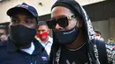 Mantan pemain timnas Brasil, Ronaldinho tiba di bandara El Galeao di Rio de Janeiro, setelah menjalani tahanan rumah di Paraguay, Selasa (25/8/2020). Pria 40 tahun itu sendiri yang mengumumkan hasil tes yang positif Covid-19 di akun Instagram-nya. (AFP/Carl dE Souza)