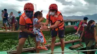 Anggota Penjaga Pantai Filipina membawa seorang anak saat mereka dievakuasi ke tempat yang lebih aman menyusul peringatan menghadapi topan Goni di provinsi Camarines Sur, Filipina (31/10/2020). (Philippine Coast Guard via AP)