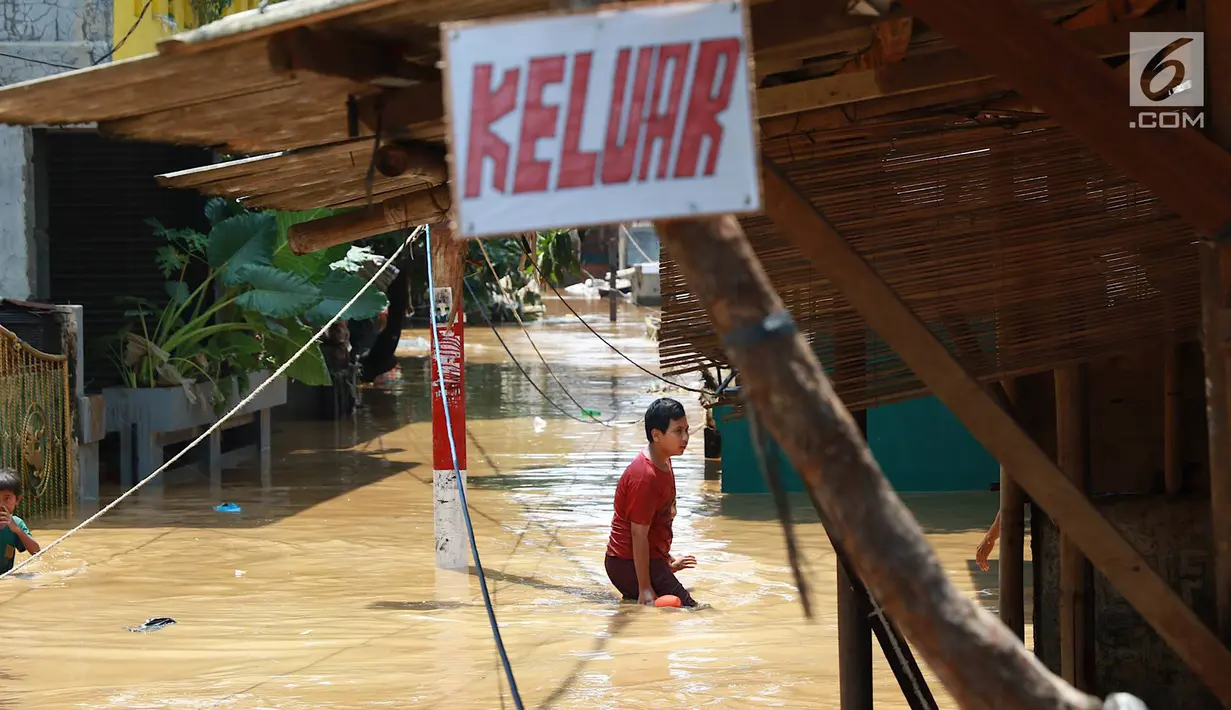Anak-anak melintasi banjir yang menggenangi kawasan Pejaten Timur, Jakarta, Jumat (26/4). Banjir yang berasal dari luapan Sungai Ciliwung tersebut merendam ratusan rumah warga hingga kedalaman lebih dari satu meter. (Liputan6.com/Immanuel Antonius)