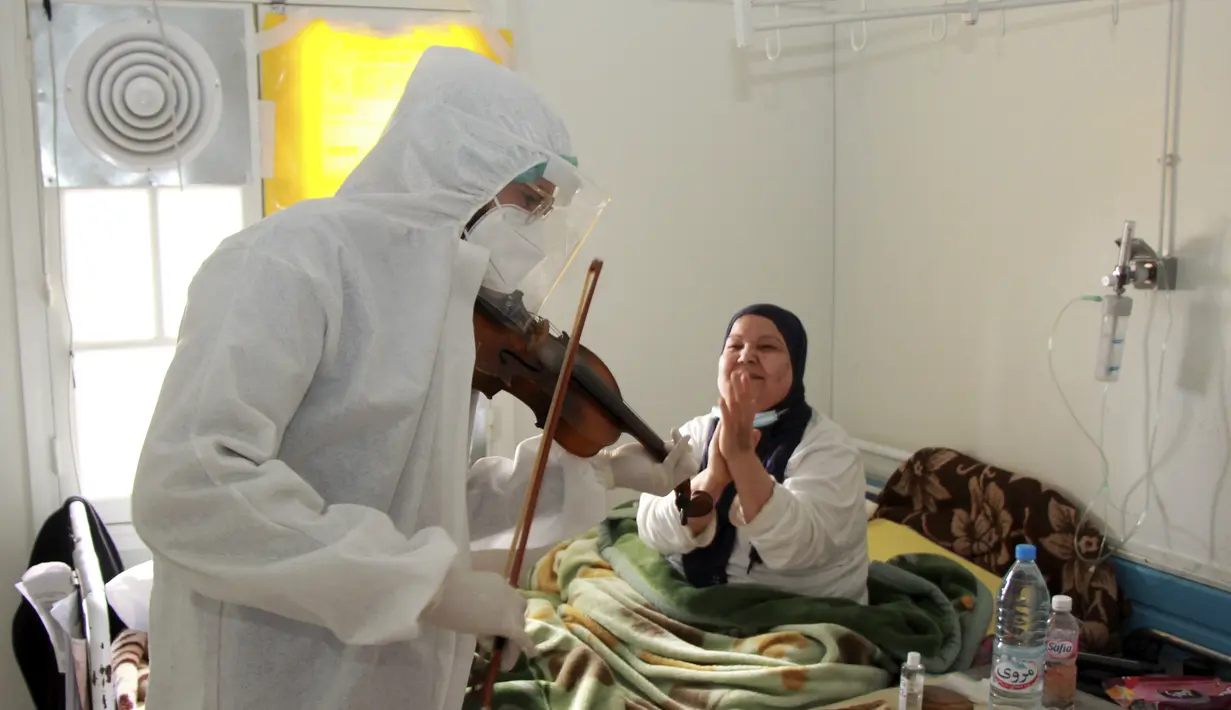 Dr. Mohamed Salah Siala memainkan biola untuk pasien di bangsal COVID-19 rumah sakit Hedi Chaker di Sfax, Tunisia, 20 Februari 2021. Ketika pemain 25 tahun itu memutuskan memainkan biolanya, dia mendapat pujian karena meningkatkan semangat pasien yang terisolasi dan membutuhkan senyuman. (AP Photo)