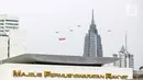 Helikopter TNI AU mengibarkan bendera Merah Putih raksasa di kawasan Gedung DPR RI, Jakarta, Selasa (5/10/2021). Bendera raksasa ini dikibarkan dari timur ke barat langit Jakarta dalam rangka memperingati Hut ke-76 TNI. (Liputan6.com/Faizal Fanani)