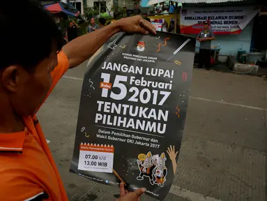Seorang warga membaca poster yang dibagikan oleh KPU saat sosialisasi Pilkada DKI 2017 di Terminal Senen, Jakarta, Minggu (18/12). Sosialisasi pesta demokrasi ini guna mencegah banyaknya pemilih yang golongan putih atau golput. (Liputan6.com/Johan Tallo)