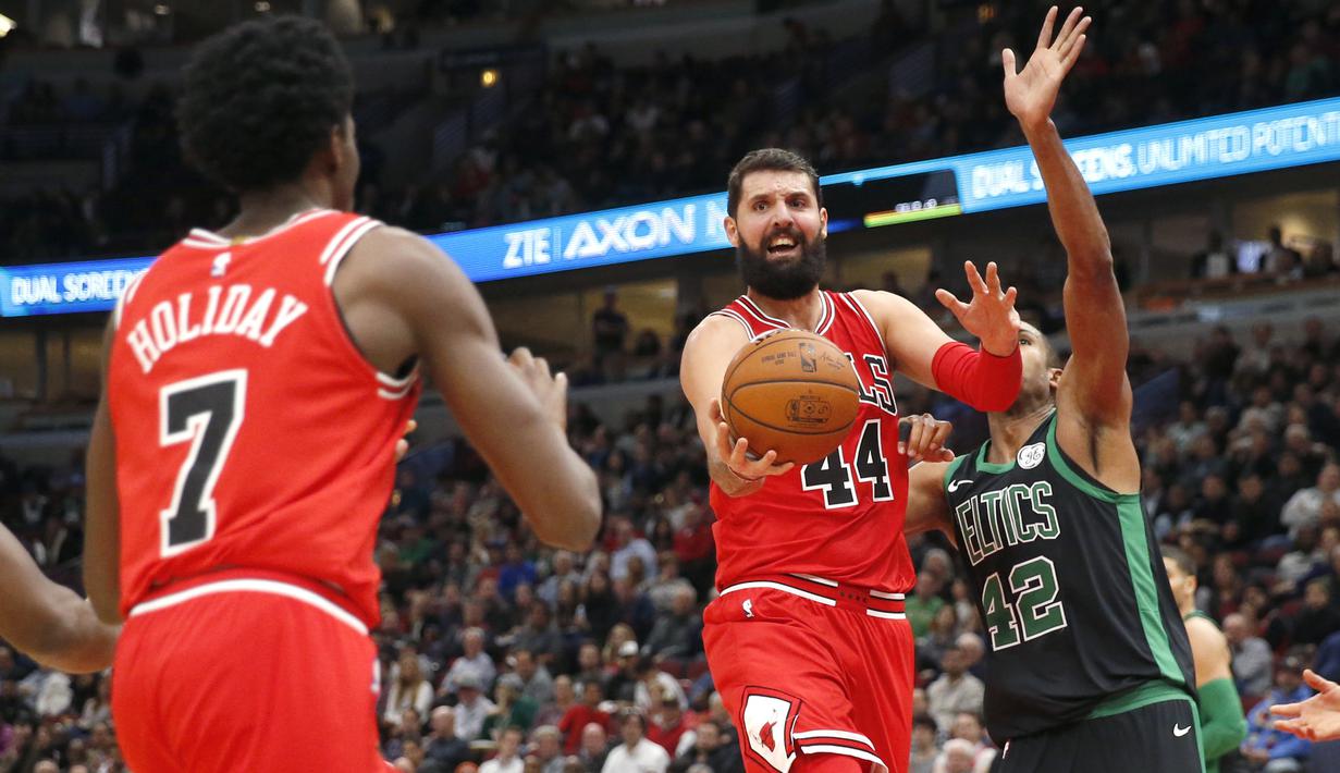 Aksi Nikola Mirotic (44) memberikan umpan kepada rekannya saat melewati pemain Boston Celtics, Al Horford (kanan) pada lanjutan NBA basketball game di United Center, Chicago, (11/12/2017). Bulls menang 108-85. (AP/Charles Rex Arbogast)