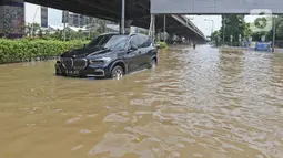 Sebuah mobil melintasi banjir di Jalan Ahmad Yani, Cempaka Putih, Jakarta, Minggu (23/2/2020). Banjir yang terjadi dari dini hari tadi melumpuhkan akses jalan tersebut. (Liputan6.com/Herman Zakharia)