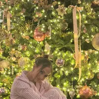 Jennifer Lopez berfoto di depan pohon Natal besar dengan ornamen yang cantik. Ia tampak mengenakan setelan piyama warna pink. [@jlo]
