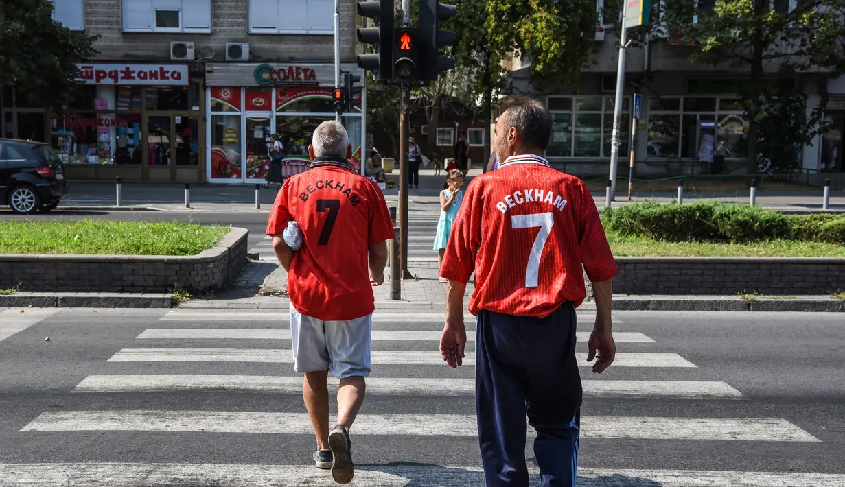 Dua pria mengenakan jersey legenda Manchester United David Beckham jelang pertandingan final UEFA Super Cup antara Real Madrid melawan MU di Philip II Arena di Skopje, Macedonia, (7 /8). (AFP Photo/Armend Nimani)