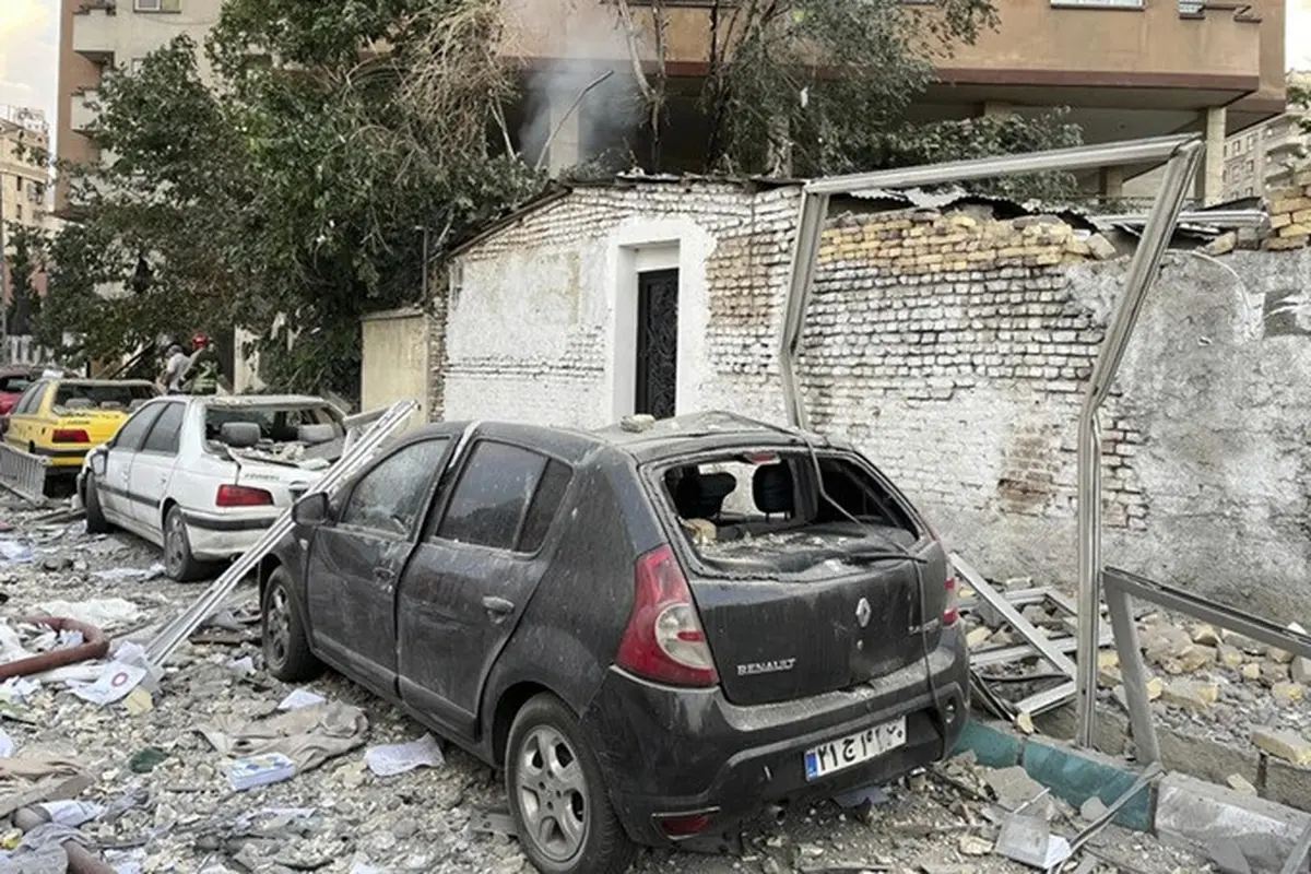 Puing-puing dari sebuah gedung apartemen terlihat di atas mobil-mobil yang diparkir setelah serangan Israel ke Teheran, Iran, Jumat, (13/6/2025).