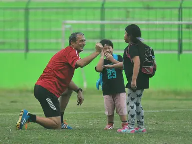 Pelatih Arema Cronus, Milomir Seslija, tampak asyik mengajak buah hati Hamka Hamzah yang bernama Gava dan Gwen bermain saat sela-sela latihan di Stadion Gajayana, Malang, Sabtu (4/6/2016). (Bola.com/Iwan Setiawan)