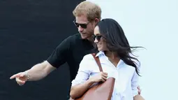 Pangeran Harry bersama Meghan Markle menghadiri pertandingan tenis kursi roda selama Invictus Games 2017 di Toronto, Kanada, Senin (25/9). Keduanya kompak mengenakan kacamata hitam selama menonton pertandingan. (Chris Jackson/GETTY IMAGES/AFP)