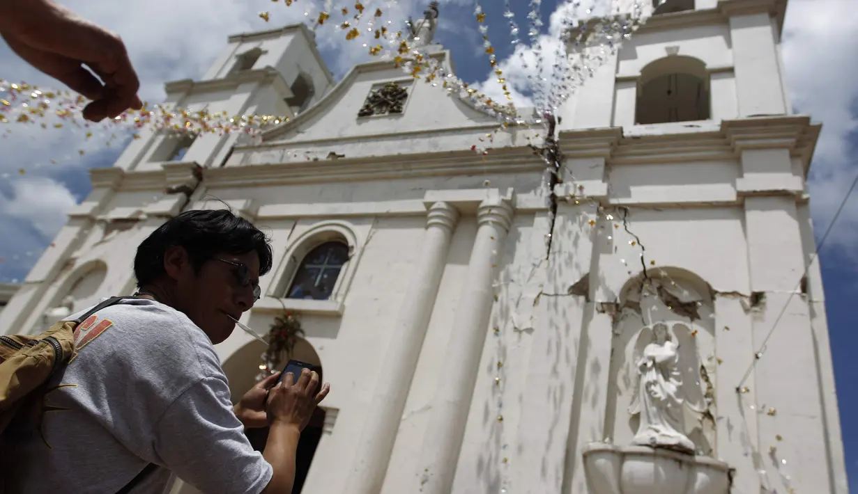 Seorang pria mengambil gambar bangunan gereja yang rusak akibat di San Pedro, wilayah San Marcos, Guatemala, Senin (7/7/14). (REUTERS/Jorge Dan Lopez)