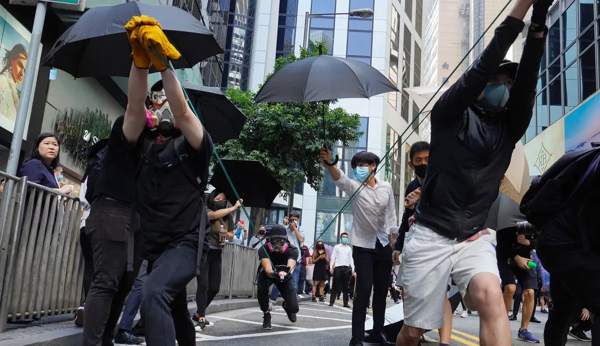 Para pengunjuk rasa menggunakan ketapel mencoba menembak saat demonstrasi di Hong Kong (11/11/2019). Ketapel hingga panahan digunakan para demonstran Hong Kong sebagai senjata saat unjuk rasa yang telah berlangsung selama lima bulan. (AP Photo/Vincent Yu)