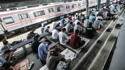 Kereta commuter line melintas dekat jemaah yang tengah salat Jumat di Stasiun Kampung Bandan, Jakarta, Jumat (7/5/2021). Sebagian jemaah menjadikan peron stasiun sebagai tempat salat dan sebagian lain berada di tangga serta jembatan penyeberangan. (merdeka.com/Iqbal S. Nugroho)