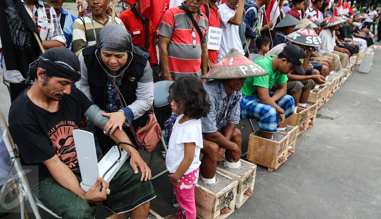 Dokter sedang mengukur tensi petani aksi protes memasung kaki dengan semen di depan Istana Merdeka, Kamis (16/3). Mereka akan terus melakukan aksi sampai bertemu dengan Presiden Jokowi. (Liputan6.com/Fery Pradolo)
