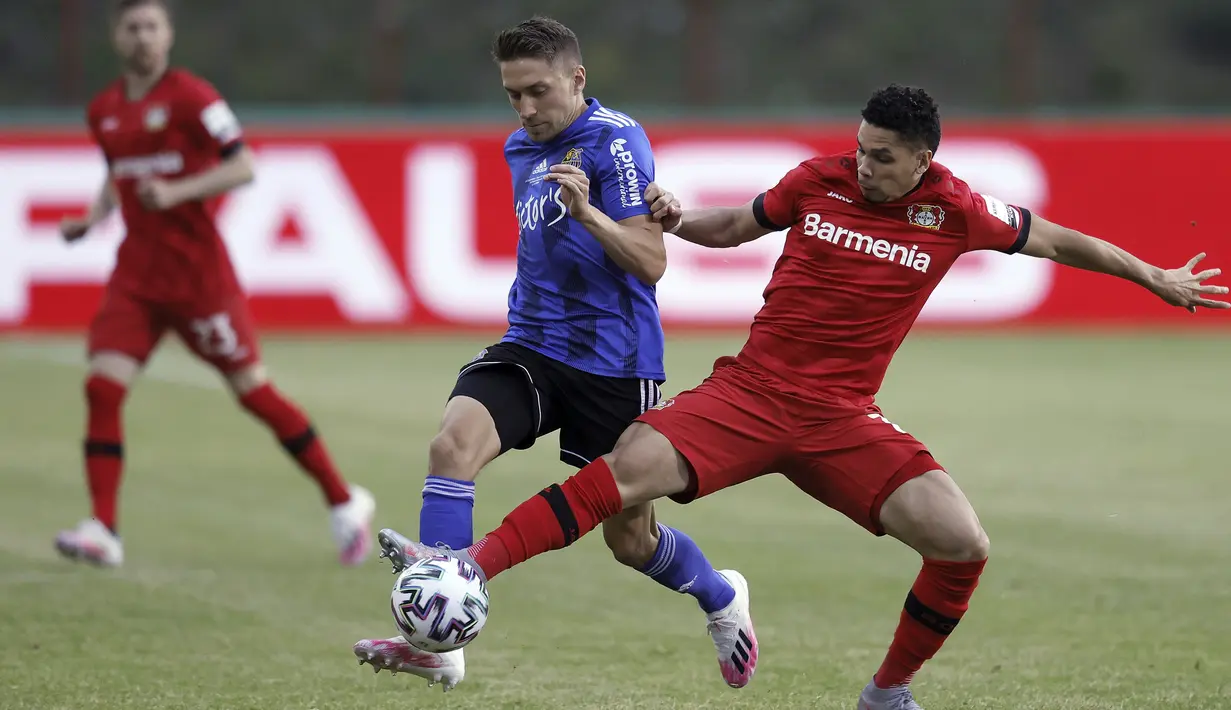 Pemain Bayer Leverkusen, Lucas Alario, duel udara dengan pemain FC Saarbruecken, Manuel Zeitz,  pada laga Piala Jerman di di Stadion Hermann Neuberger, Voelklingen, Selasa (9/6/2020). Bayer Leverkusen menang 3-0 atas FC Saarbruecken. (AP/Ronald Wittek)