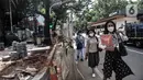 Pejalan kaki melintasi jalur sementara saat proyek revitalisasi trotoar di Jalan Medan Merdeka Selatan, Jakarta Pusat, Selasa (22/11/2022). Pemprov DKI Jakarta mengalokasikan anggaran sebesar Rp 171 miliar dalam Rancangan Anggaran Pendapatan dan Belanja Daerah (RAPBD) DKI Jakarta 2023 untuk revitalisasi trotoar di Ibu Kota. (merdeka.com/Iqbal S. Nugroho)