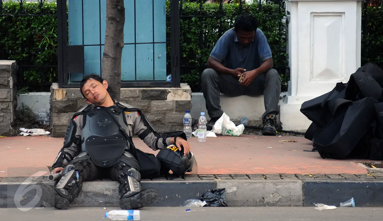 Seorang polisi tertidur di pinggir Jalan Merdeka Barat, Jakarta, Jumat (4/11). Ribuan aparat gabungan berjaga saat massa melakukan aksi di depan Istana Negara menuntut penegakan hukum kasus dugaan penistaan agama. (Liputan6.com/Helmi Fithriansyah)