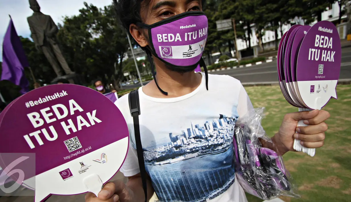 Massa Aliansi Jurnalis Independen melakukan aksi damai dengan membagikan masker dan kipas kepada pengendara di Jakarta, Selasa (3/5). AJI juga menyatakan bahwa musuh kebebasan pers 2016 adalah kepolisian. (Liputan6.com/Immanuel Antonius)