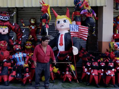 Seorang penjual pinata berdiri di depan dagangannya sebelum perayaan tradisional, Pembakaran Iblis di Guatemala City, Guatemala (7/12). Pinata adalah permainan yang biasanya ditujukan untuk anak-anak kecil saat merayakan pesta. (Reuters/Luis Echeverria)