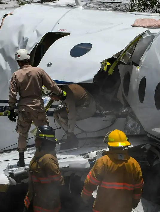 Petugas pemadam kebakaran berada di lokasi pesawat jet pribadi Gulfstream G200 yang tergelincir dari landasan saat mendarat di Bandara Tegucigalpa, Honduras, Selasa (22/5). Pesawat itu terbang dari Austin, Texas pada Selasa pagi. (AFP/Orlando SIERRA)