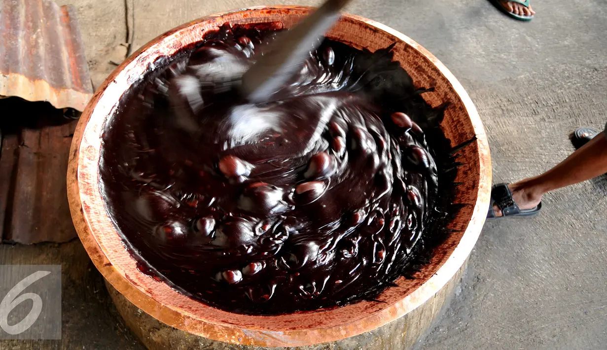 Pekerja mengaduk dodol di industri rumah kawasan Pasar Minggu, Jakarta, Kamis (23/6). Harga Dodol Betawi rasa ketan putih dan ketan item dijual mulai dari harga Rp50 ribu per besek.  (Liputan6.com/Gempur M Surya)