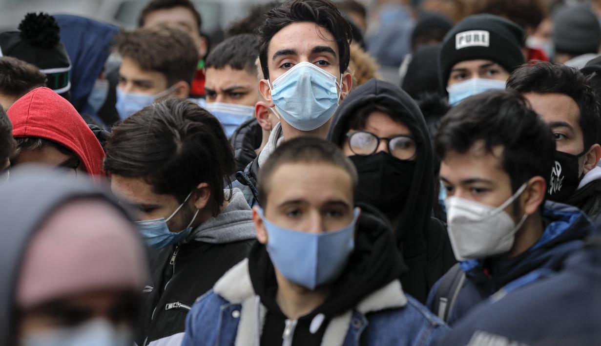 Para remaja mengantre di luar restoran untuk mendapatkan burger gratis yang ditawarkan selama acara promosi di Bucharest, Rumania, Senin (1/2/2021). Ratusan orang berkerumun demi burger gratis hingga polisi mendenda restoran karena tidak mematuhi protokol COVID-19. (AP/Vadim Ghirda)