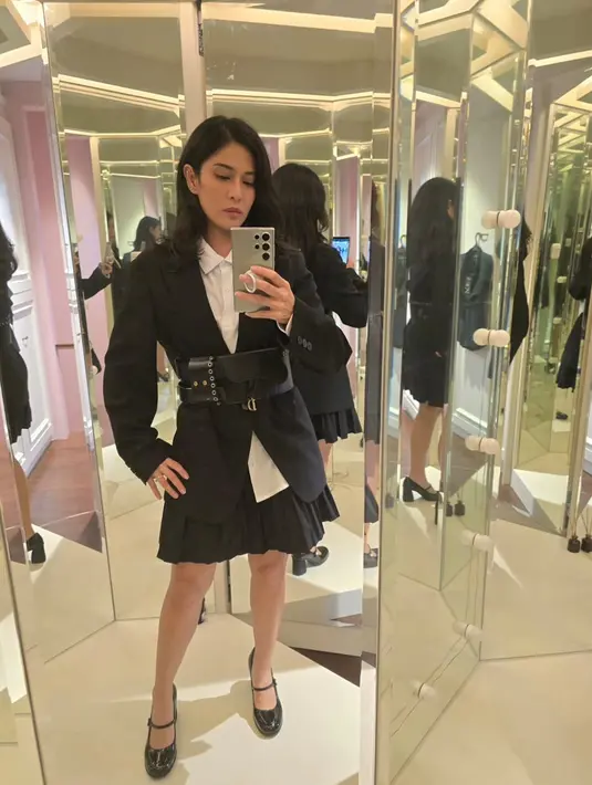 Dian Sastrowardoyo tampak padukan kemeja putih dengan blazer hitam dan rok mini ruffle. Belt bag dari Dior hitam bentuk siluet pinggang Dian [@therealdisastr]