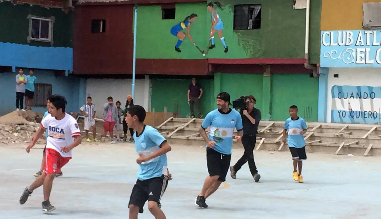 Bintang sepak bola David Beckham bermain sepak bola bersama anak-anak di kawasan pemukiman kumuh 1-11-14 di Buenos Aires, Senin (9/11/2015). Beckham berada Argentina untuk membuat film dokumenter tentang sepak bola. (AFP/FIXER-Argentina/Macarena GAGLIARD)