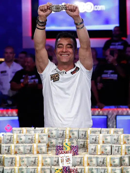Pemain poker Hossein Ensan berpose dengan tumpukan uang sambil menunjukkan sebuah gelang usai memenangkan World Series of Poker di Las Vegas, Amerika Serikat, Rabu (17/7/2019). Ensan berhak membawa pulang hadiah sebesar 10 juta dolar AS atau sekitar Rp 139.750.000.000. (AP Photo/John Locher)