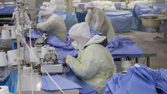 Pekerja memproduksi pakaian pelindung di sebuah pabrik di Nantong, Provinsi Jiangsu, China, Senin (27/1/2020). Pakaian pelindung tersebut diproduksi untuk mendukung pasokan bahan medis saat wabah virus corona melanda China. (STR/AFP)
