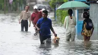 Seorang warga bersama anjingnya melewati banjir di Colombo, Senin (16/5). Pejabat pemerintah terkait juga memerintahkan untuk membangun kanal guna mengendalikan banjir serta menanggulangi tanah longsor terulang lagi. (Lakruwan Wanniarachchi/AFP)