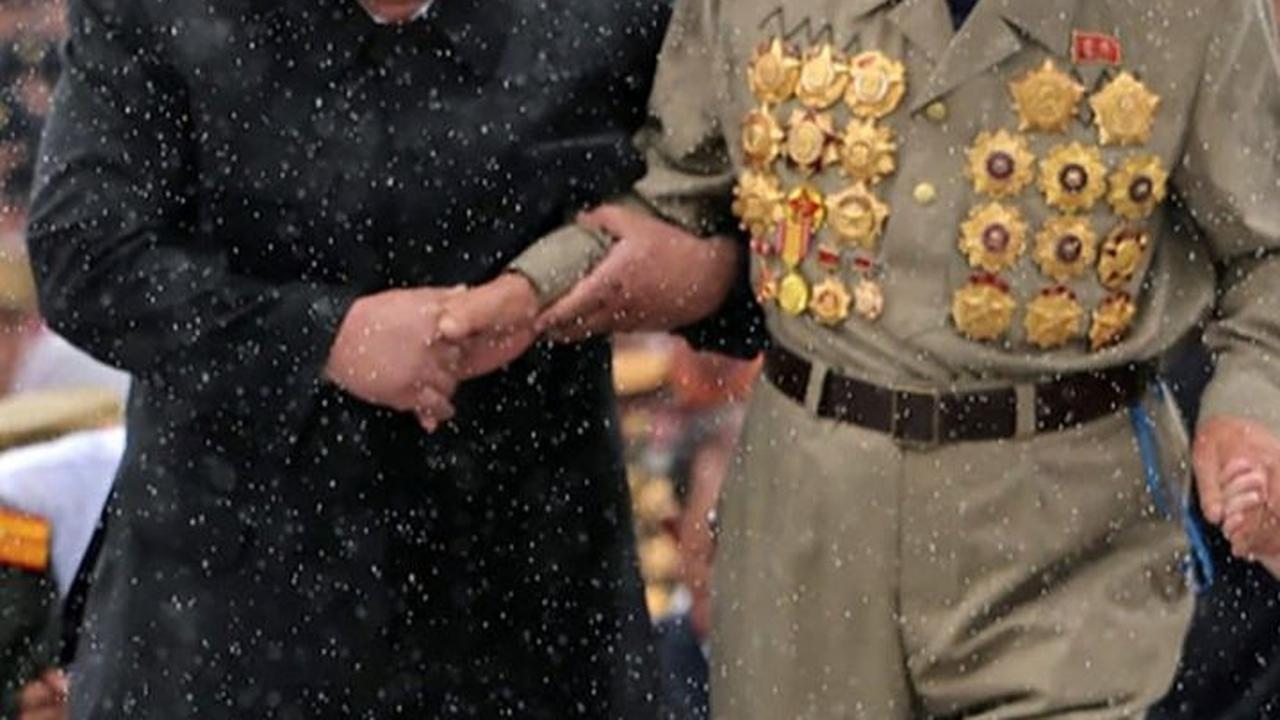 Kim Jong-un, tanpa ragu, rela berbasah-basahan demi mengenang jasa para martir. Foto: STR / KCNA VIA KNS / AFP<br>
