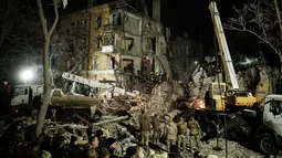 Tim penyelamat memindahkan puing-puing untuk mencari korban selamat di gedung apartemen yang hancur terkena roket pada malam hari di pusat kota Kramatorsk, Ukraina timur, pada Rabu (1/2/2023). Sejumlah pejabat lokal Ukraina melaporkan bahwa satu gedung apartemen hancur total akibat serangan rudal itu. (Yasuyoshi CHIBA / AFP)