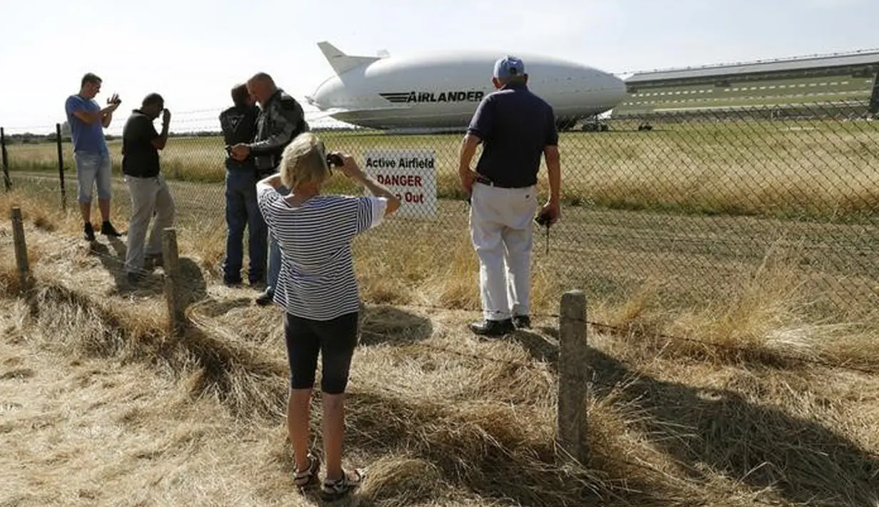 Sejumlah orang mengambil gambar dari pesawat Airlander 10 setelah gagal mendarat di Cardington Airfield, Inggris, Rabu (24/8). Pesawat yang diklaim terbesar di dunia itu rusak karena harus menukik tajam ketika melakukan pendaratan (REUTERS/Darren Staples)
