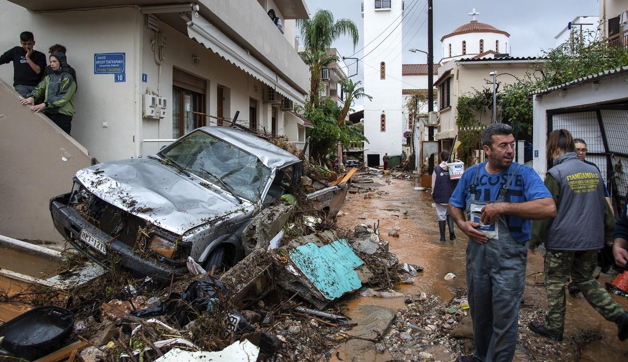 Warga mencoba membersihkan jalan dari puing-puing setelah hujan lebat di desa Malia, pulau Kreta, Yunani, Selasa (10/11/2020). Banjir besar di Pulau Kreta Yunani merusak jalan, membanjiri ratusan rumah, dan menyeret mobil ke laut di tengah hujan deras yang sedang berlangsung. (AP Photo/Harry Nakos)
