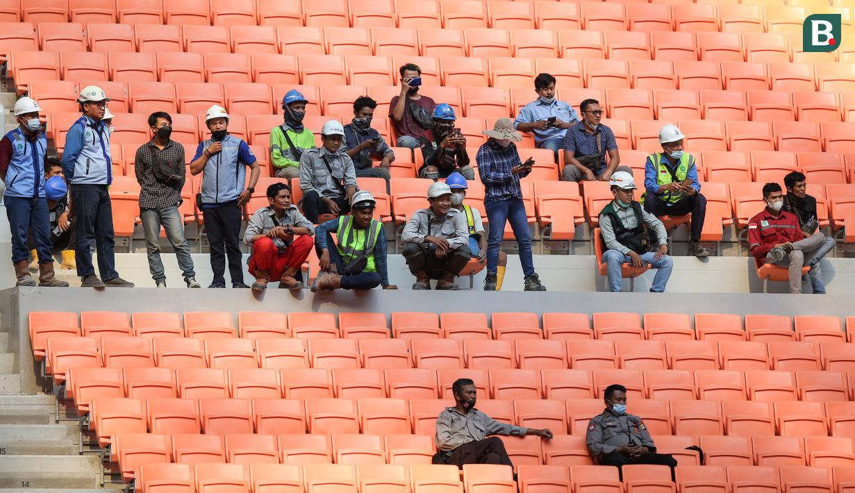 Pekerja proyek pembangunan JIS ikut menyaksikan laga pembuka International Youth Championship 2021 antara Bali United U-18 melawan Atletico Madrid U-18 di Jakarta International Stadium, Jakarta, Rabu (13/04/2022). (Bola.com/Bagaskara Lazuardi)
