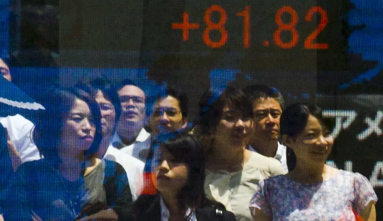 Sejumlah orang tercermin dalam papan yang menampilkan indeks saham di Tokyo, Jepang, Jumat, (10/7/ 2015). Harga saham Nikkei mengalami perubahan mengikuti gejolak pasar Tiongkok. (REUTERS/Thomas Peter)