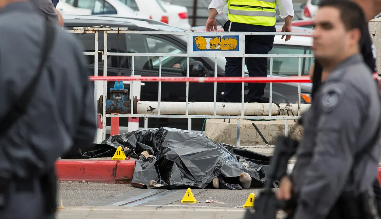 Petugas berdiri dekat mayat pria Palestina yang ditembak mati usai menikam dua warga Israel di Tel Aviv, Kamis (8/10). Menurut juru bicara polisi Israel, pria Palestina itu menikam tentara wanita dengan obeng di Mulailah Street. (AFP PHOTO/JACK GUEZ)