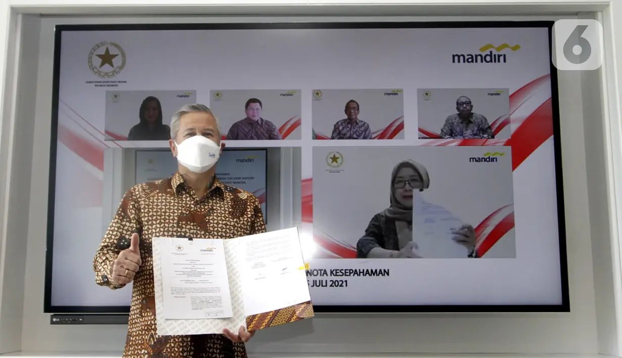 Rohan Hafas menunjukkan MoU Kerjasama Kemensetneg dan Bank Mandiri disaksikan Mensesneg Pratikno, Sekretaris Setya Utama, Deputi Administrasi Aparatur Kemensetneg Nanik Purwanti, Dirut Bank Mandiri Darmawan Junaidi dan Wadirut (di layar LED) di Jakarta, Kamis (15/7/2021). (Liputan6.com/HO/Mandiri)