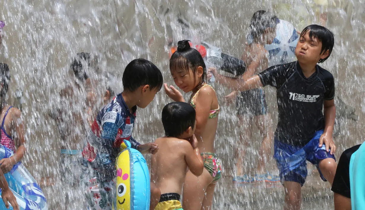 Anak-anak bermain di air di sebuah taman di Tokyo, Jepang, (16/7). Badan Meteorologi nmengatakan gelombang panas terus berlanjut di wilayah metro ketika suhu naik mencapai 35 derajat Celcius (95 derajat Fahrenheit). (AP Photo/Koji Sasahara)
