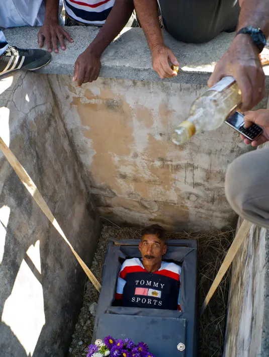 Divaldo Aguiar berbaring didalam peti matinya diturunkan ke dalam liang kubur saat festival Burial of Pachencho di Santiago de Las Vegas, Kuba (5/2). Asal nama “Pachencho” diambil dari judul kisah yang dimainkan teater setempat. (AP Photo/Ramon Espinosa)