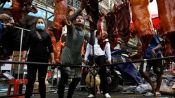Seorang penjual (tengah) memilih babi panggang untuk pelanggannya di pasar menjelang Tahun Baru Imlek di Phnom Penh, Kamboja, Senin (31/1/2022). Tahun Baru Imlek mengawali Tahun Macan pada 1 Februari. (AFP/Tang Chhin Sothy)