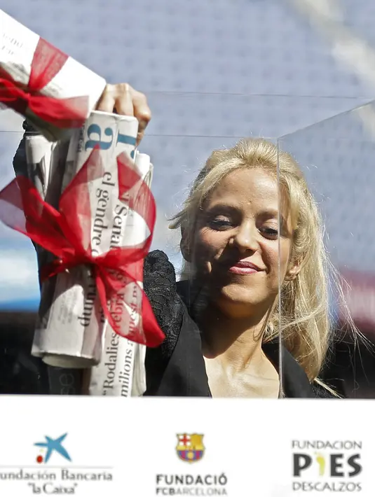 Penyanyi Kolombia, Shakira mengambil gulungan surat kabar dalam acara amal bersama Barcelona FC di Stadion Camp Nou, Spanyol, Selasa (28/3). Duta UNICEF itu akan membangun sekolah bekerja sama dengan klub Barcelona dan Yayasan La Caixa.( PAU BARRENA/AFP)