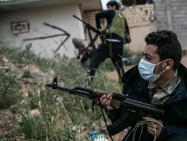 Seorang pasukan Pemerintah Kesepakatan Nasional (GNA) dukungan PBB yang mengenakan masker melepaskan tembakan ke arah pasukan Tentara Nasional Libya (LNA) yang berbasis di timur dalam pertempuran di garis depan Ain-Zara di Tripoli, Libya, (25/3/2020). (Xinhua/Amru Salahuddien)