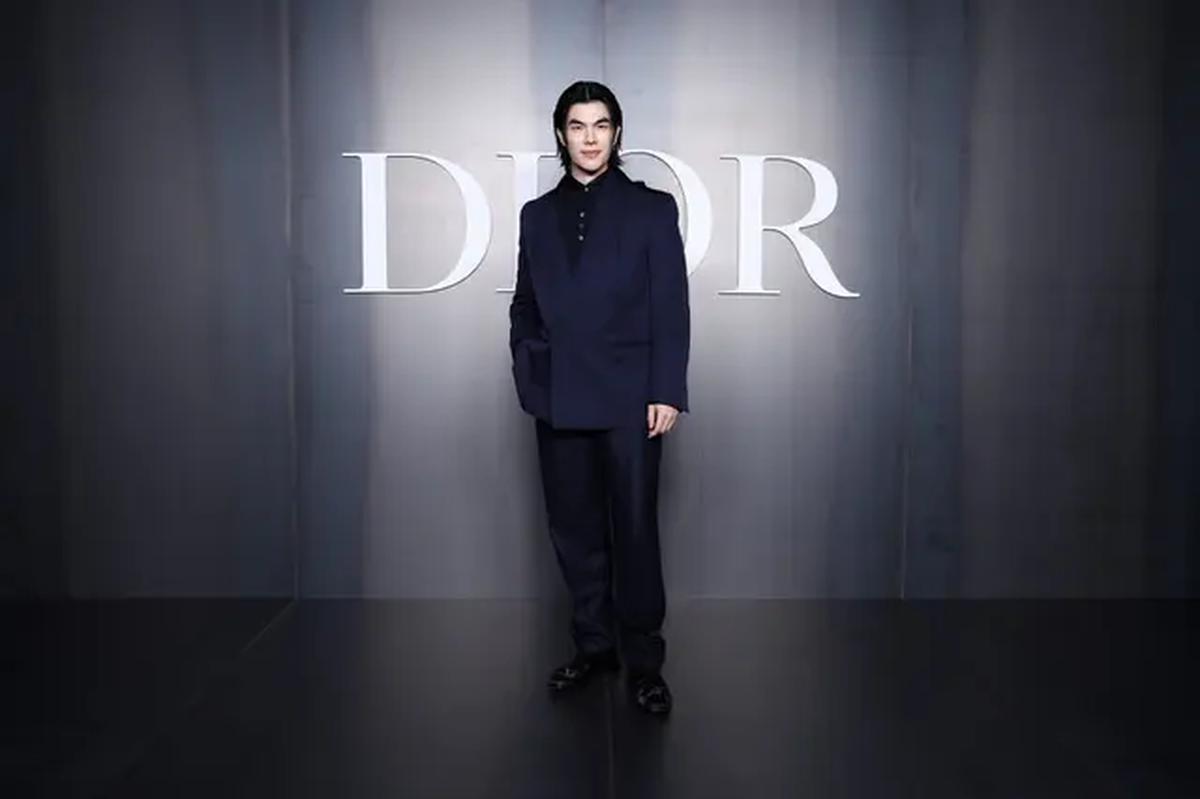 Mile, rekan senegara Apo ini memilih setelan navy yang dipadukan dengan loose pants hitam dan kemeja senada. Kombinasi warna gelap ini membuat penampilannya terlihat gagah dan sophisticated. [Dok/DIOR].