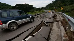 Sebuah mobil melewati jalanan retak setelah diguncang gempa 7,8 SR di Chone, Ekuador, Minggu (17/4). Menurut pihak berwenang, gempa kuat tersebut setidaknya menewaskan 246 orang dan menghancurkan bangunan serta jembatan. (Juan Cevallos/AFP)
