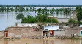 Orang-orang berdiri di rumah mereka yang terendam banjir setelah hujan lebat di distrik Nowshera, Provinsi Khyber-Pakhtunkhwa, Pakistan pada tanggal 16 April 2024. (Abdul MAJEED/AFP)