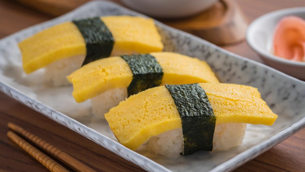 Sushi Telur Tamago manis gurih dengan tamagoyaki lembut di atas nasi sushi, dibungkus dengan selembar nori