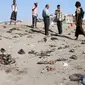 Sejumlah orang berkumpul di lokasi bom bunuh diri yang menyasar sebuah pangkalan militer kota Aden, Yaman, Minggu (18/12). Seorang anggota militer menyebut pelaku membaur di antara para tentara di pangkalan al-Solba. (SALEH AL-OBEIDI/AFP)